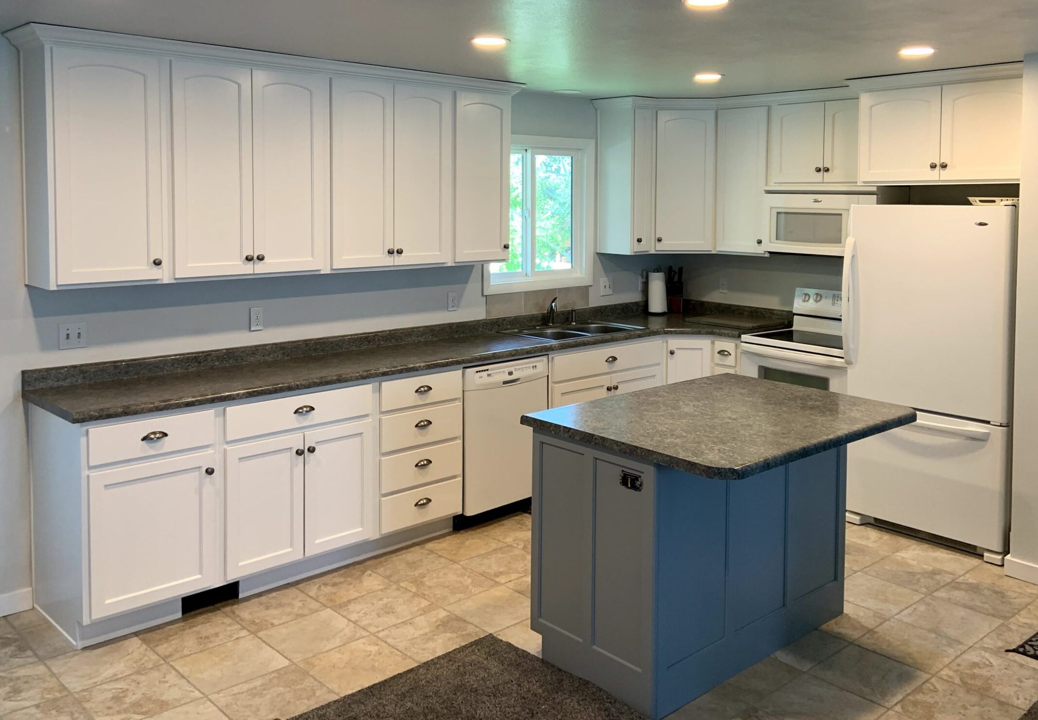 Kitchen remodel featuring white cabinets and blue island refinishing